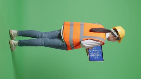 Full Body Back View Of Asian Female Engineer With Safety Helmet Looking At The Wind Turbine Blueprint On Laptop While Standing In The Green Screen Background Studio