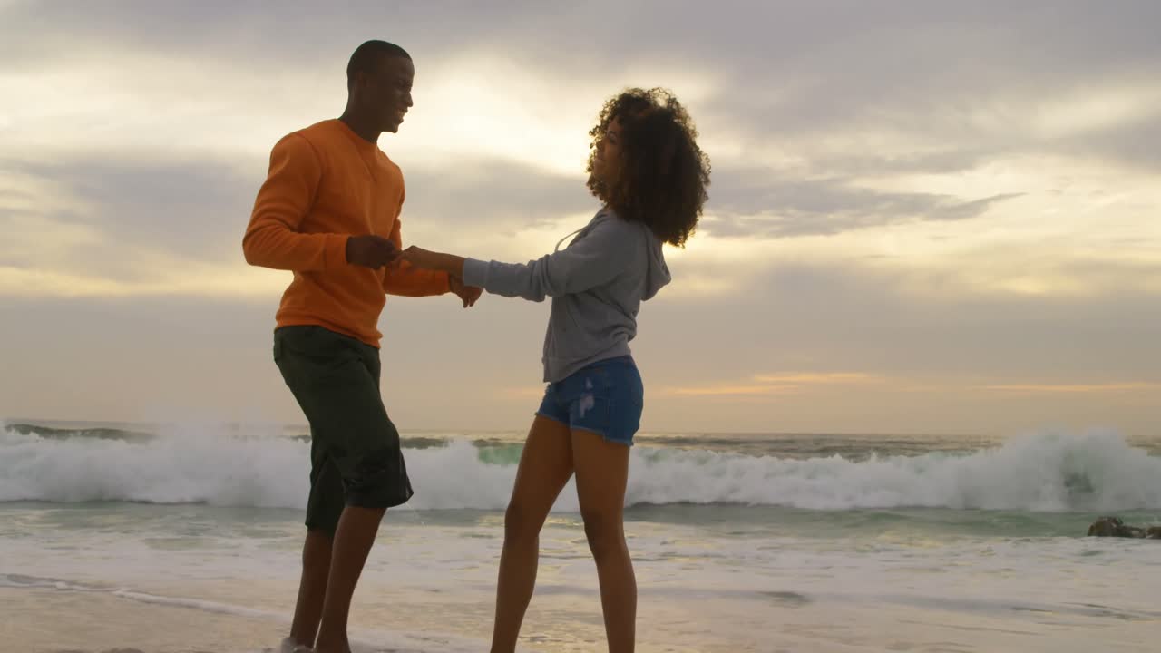 Side view of African american couple embracing each other on the beach 4k