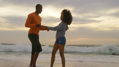 Side-view-of-African-american-couple-embracing-each-other-on-the-beach-4k