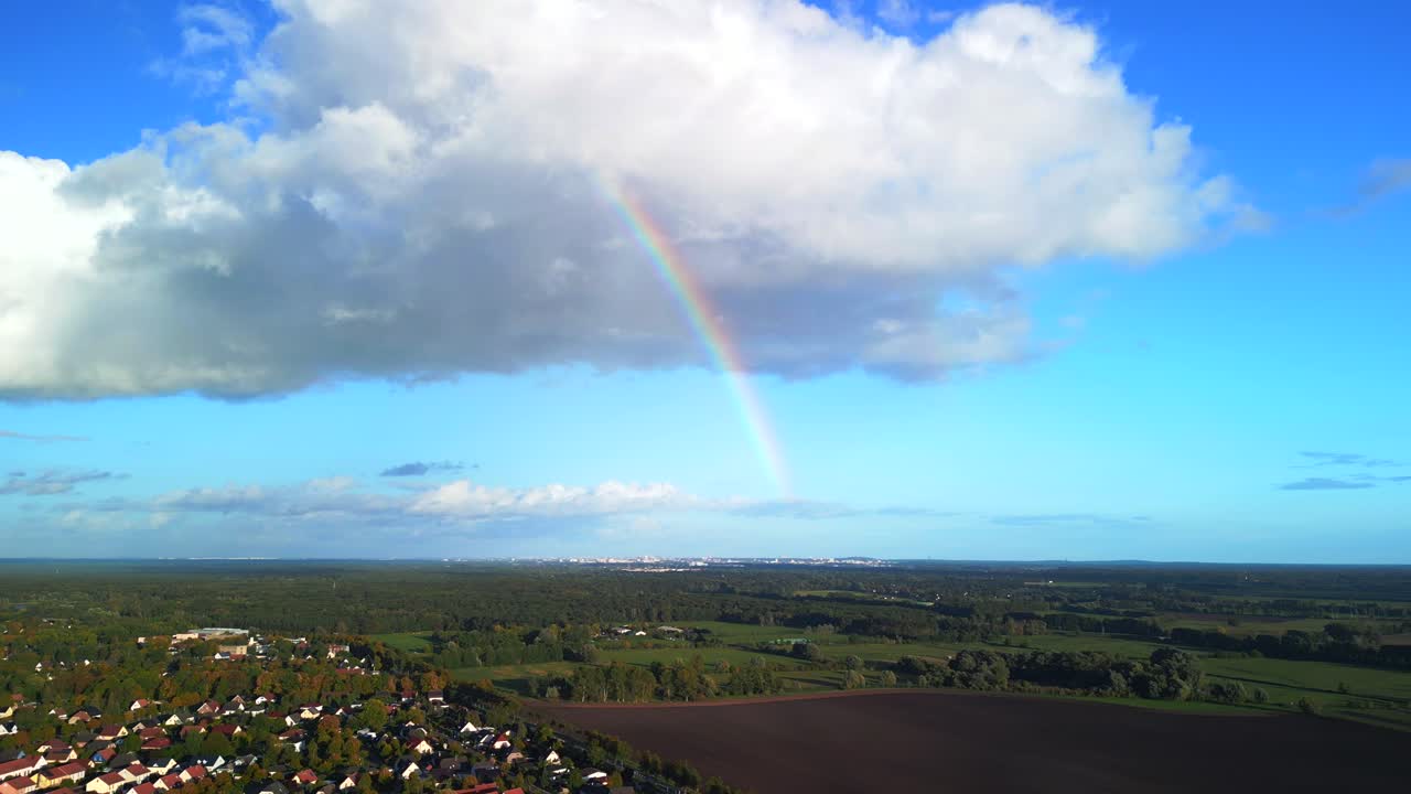 arco iris de una nube blanca sobre un pequeño pueblo
