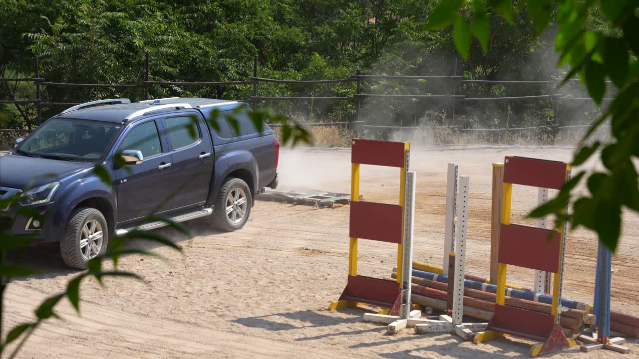 Static shot of a utility car with a drag moving between obstacles to repair horse riding area