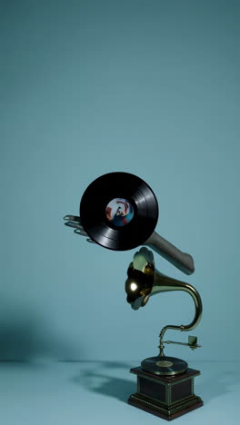 hand holding a vinyl record over a vintage gramophone