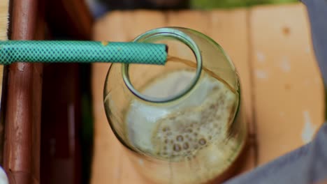 High-angle-shot-of-Fresh-apple-juice-coming-out-of-a-pipe-in-the-juice-glass-jars