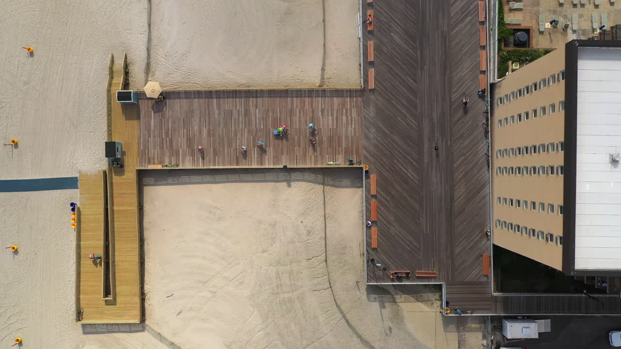 dron de arriba hacia abajo, vista de pájaro sobre el paseo marítimo, pájaros volando - gente caminando - andando en bicicleta, luego la cámara del dron gira a la izquierda