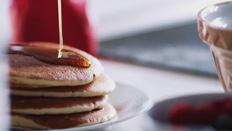 jarabe de arce que se vierte en una pila de panqueques o crepes recién hechos en la mesa para el día de los panqueques