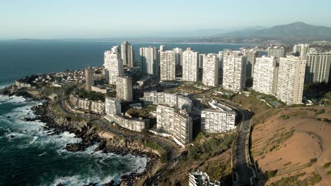 Panoramic-aerial-orbit-of-concon-with-its-tall-buildings-at-sunset-with-mauco-hill-and-mountains-in-the-background