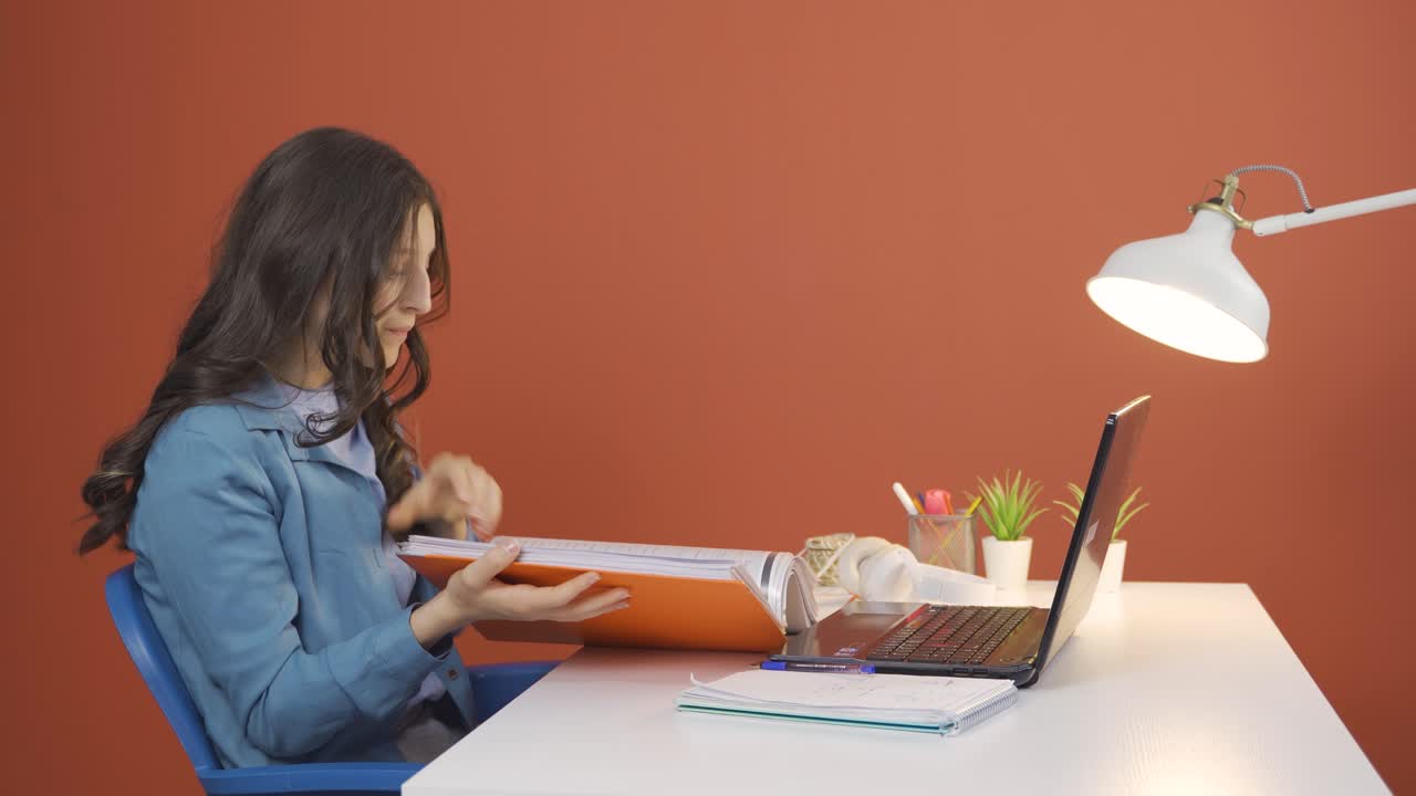 노트북에서 일하는 젊은 여성이 화를 내며 파일을 던집니다.