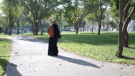 woman in hijab and abaya walking in a park
