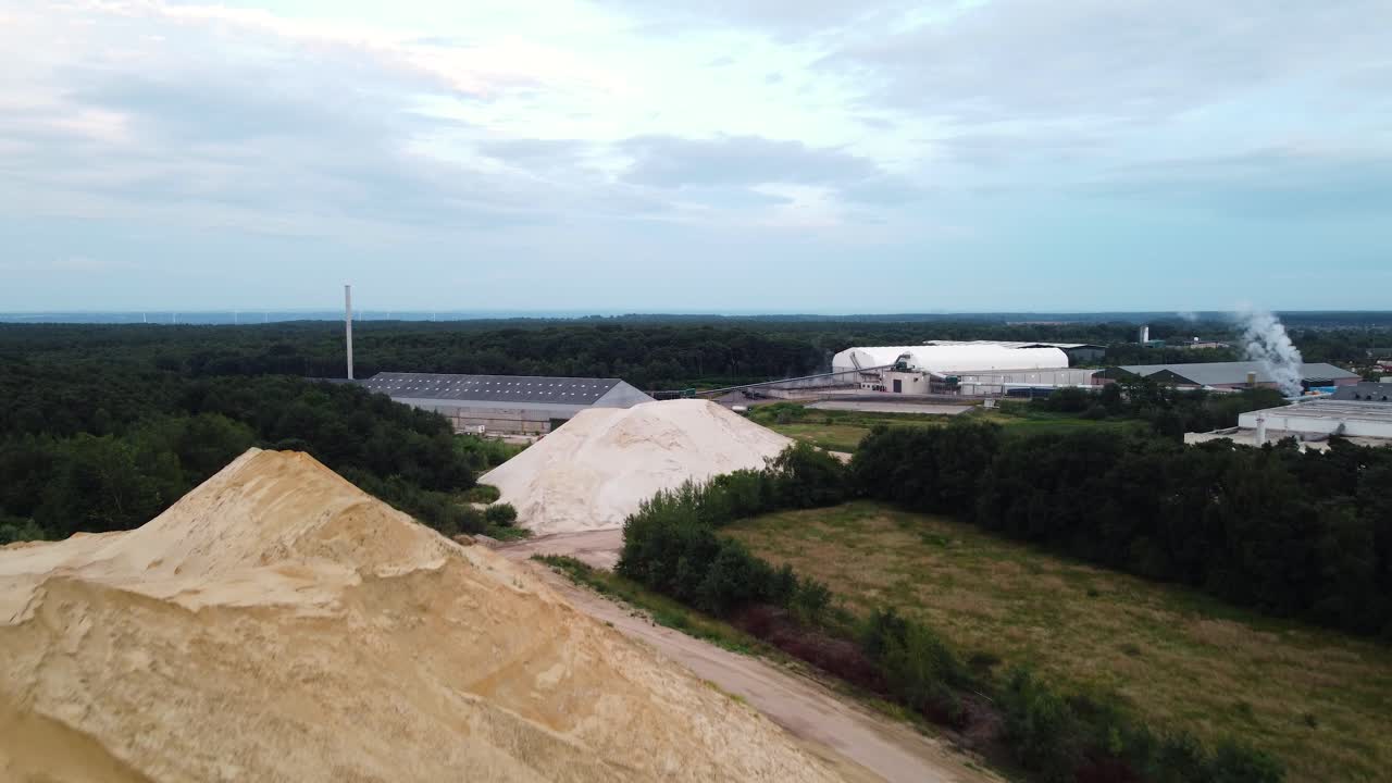 Cantiere con enormi cumuli di terra in una moderna area industriale, vista aerea