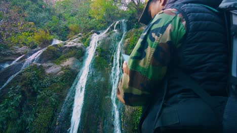 un excursionista toma una foto de una magnífica cascada con su teléfono en la parte superior de las montañas del atlas de argelia
