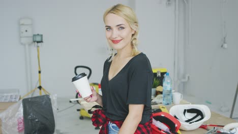 mujer sonriente con vaso de papel en el taller