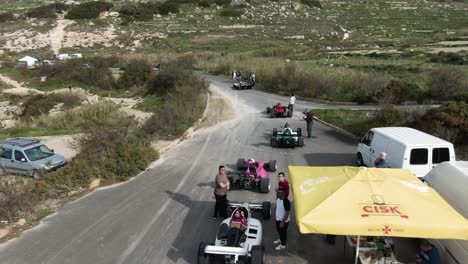 customized racing cars waiting for the race to start at the starting point of the road track at the hill in imtahleb malta - aerial shot