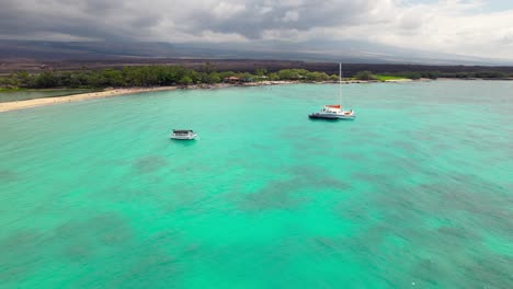 big island hawaiian anaehoomalu bay boats sailing on tropical turquoise ocean landscape aerial flyover shot