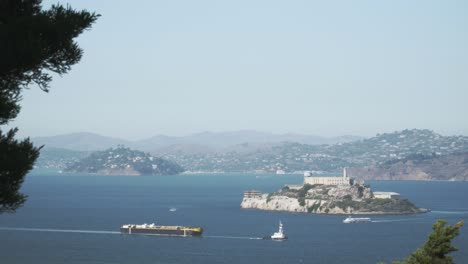Ein-Frachtschiff-Und-Boote,-Die-An-Einem-Ruhigen-Sonnigen-Tag-In-San-Francisco-An-Der-Historischen-Insel-Alcatraz-Vorbeifahren
