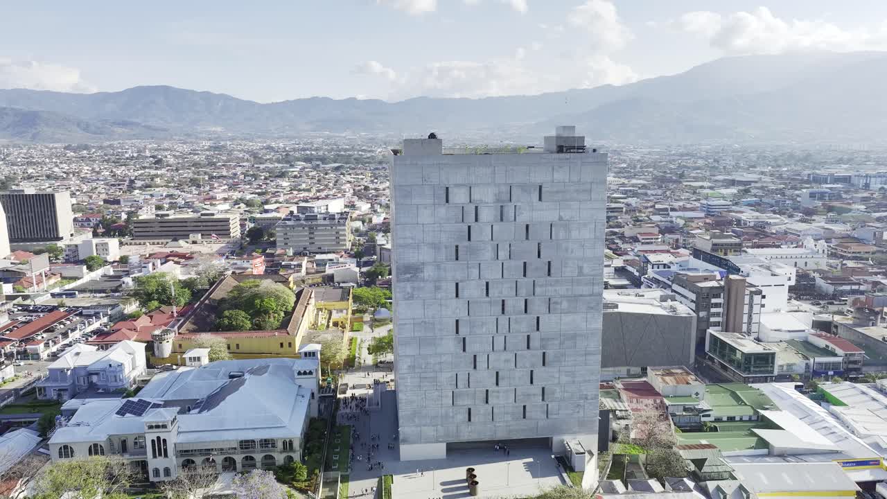 Costa Rica's Parliament building from a unique perspective, aerial drone shot with the camera rotating around the iconic brutalist structure, showcasing its bold architectural design