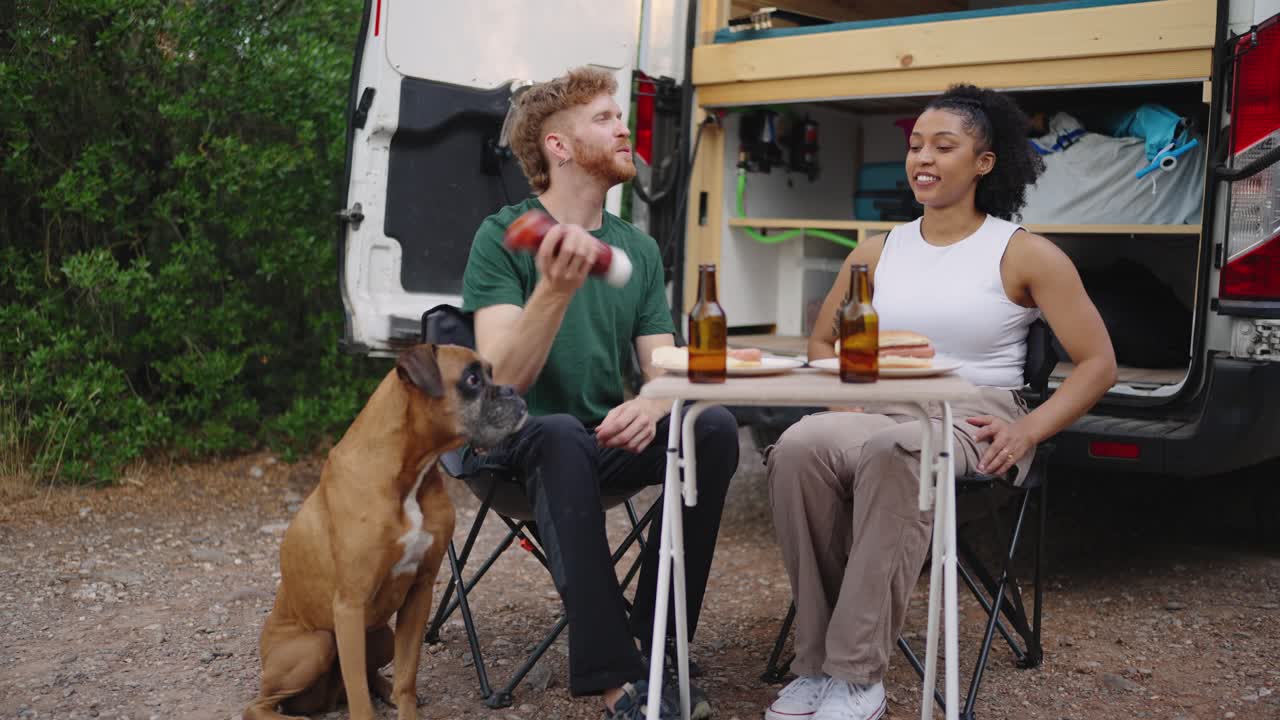 Couple enjoying food outside van with their dog
