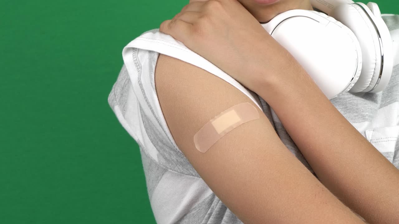 niño adolescente mostrando su brazo con yeso después de la vacunación en el fondo de la pantalla verde. vacuna y atención médica durante la pandemia de covid-19