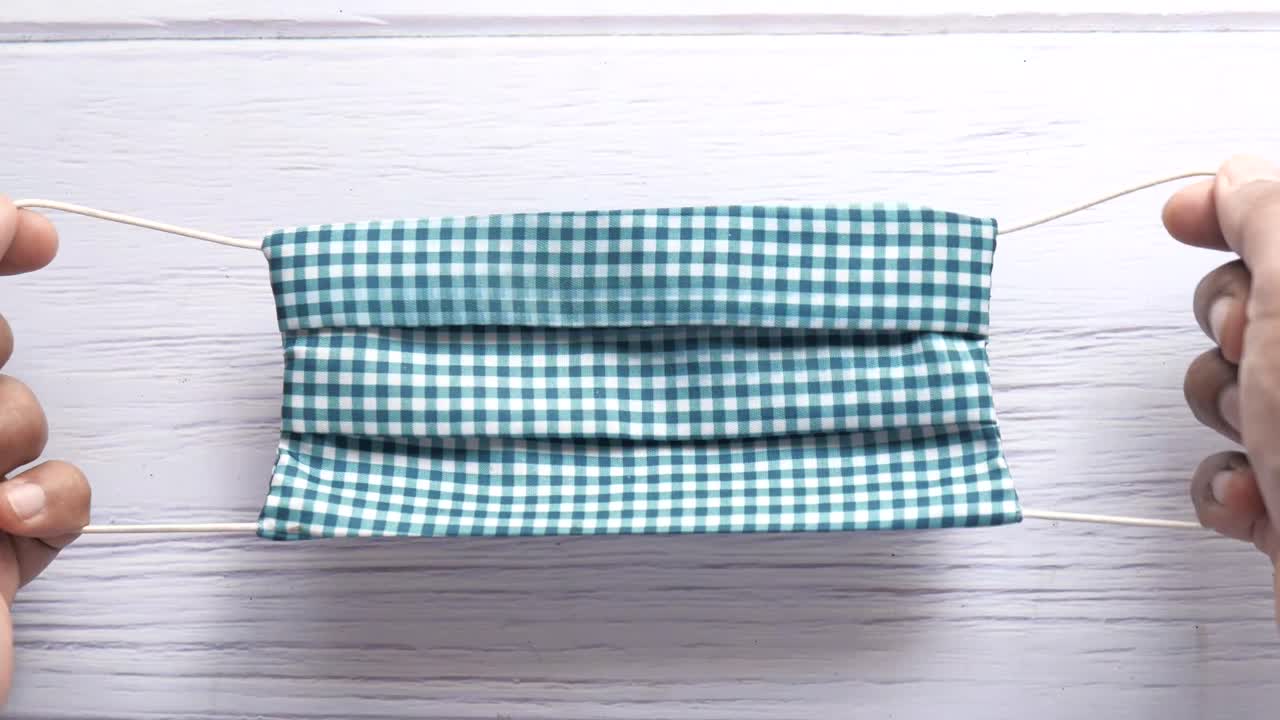 플레이드 얼굴 마스크를 들고 있는 사람