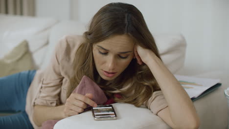 Teléfono-De-Desplazamiento-De-Mujer-Joven-En-Casa.-Primer-Plano-De-Una-Mujer-Feliz-Usando-Un-Teléfono-Inteligente