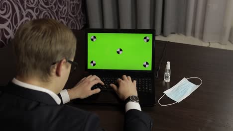 hombre está escribiendo en el teclado de la computadora portátil con pantalla verde, tecla de croma. trabajo a distancia