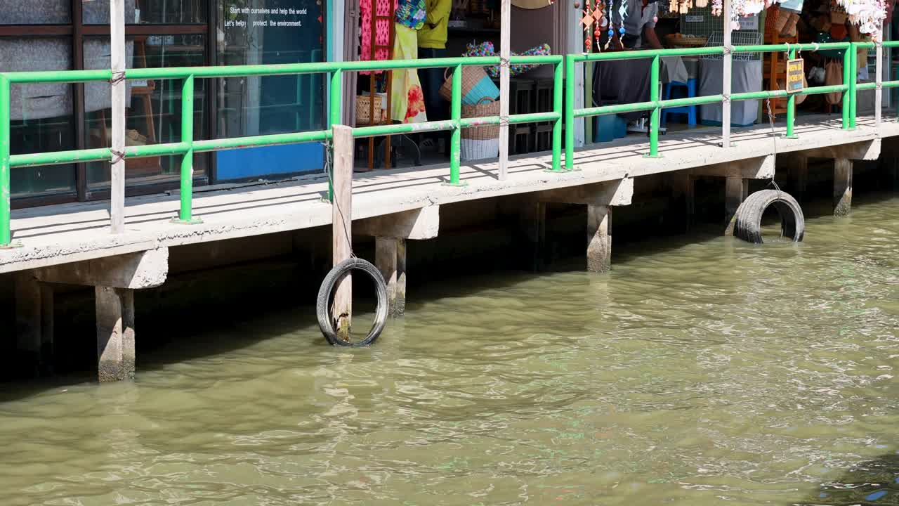A vibrant scene at Bangkok's Khlong Lat Mayom Floating Market, showcasing colorful shops along a bustling waterfront