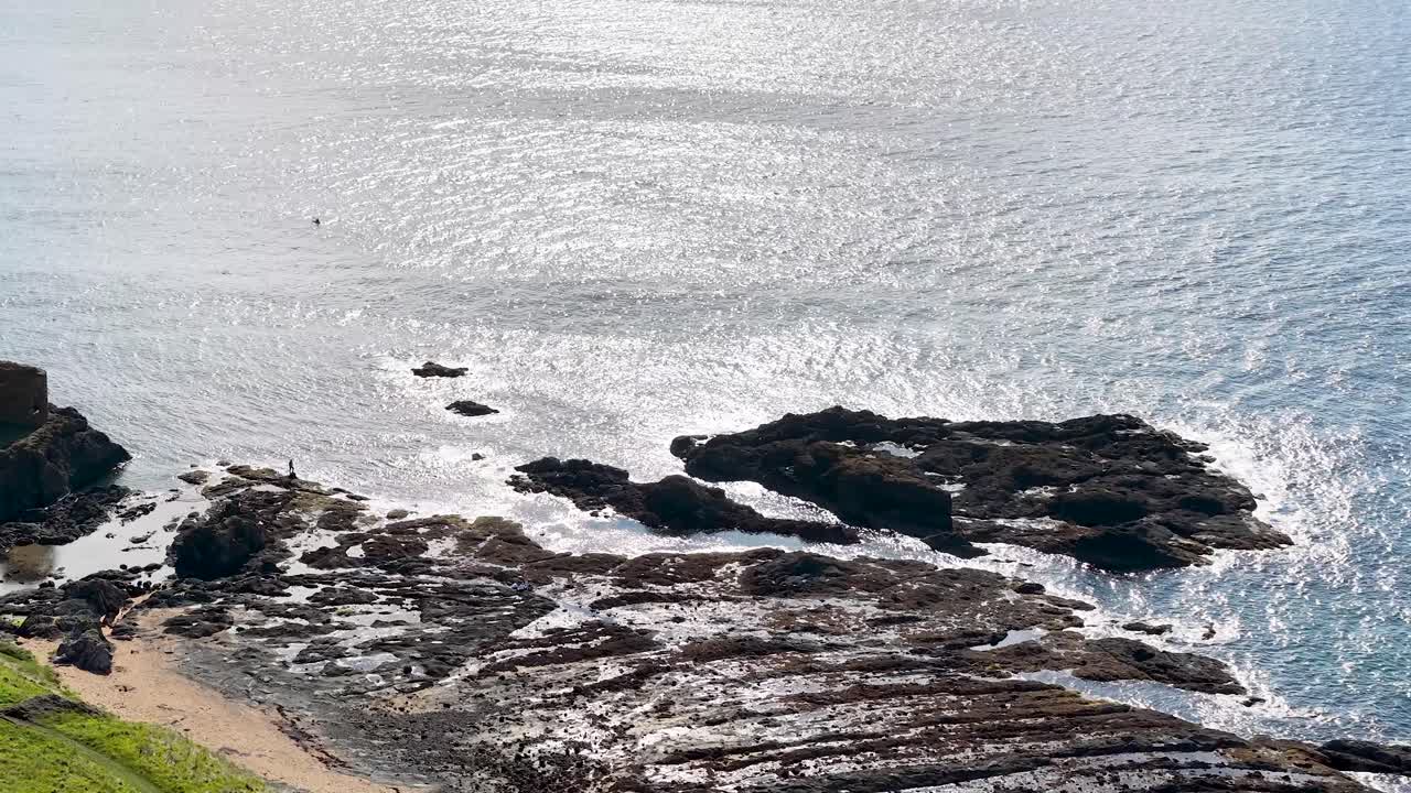 Drone glides above Fife’s rocky shore, revealing sparkling ocean under bright natural daylight