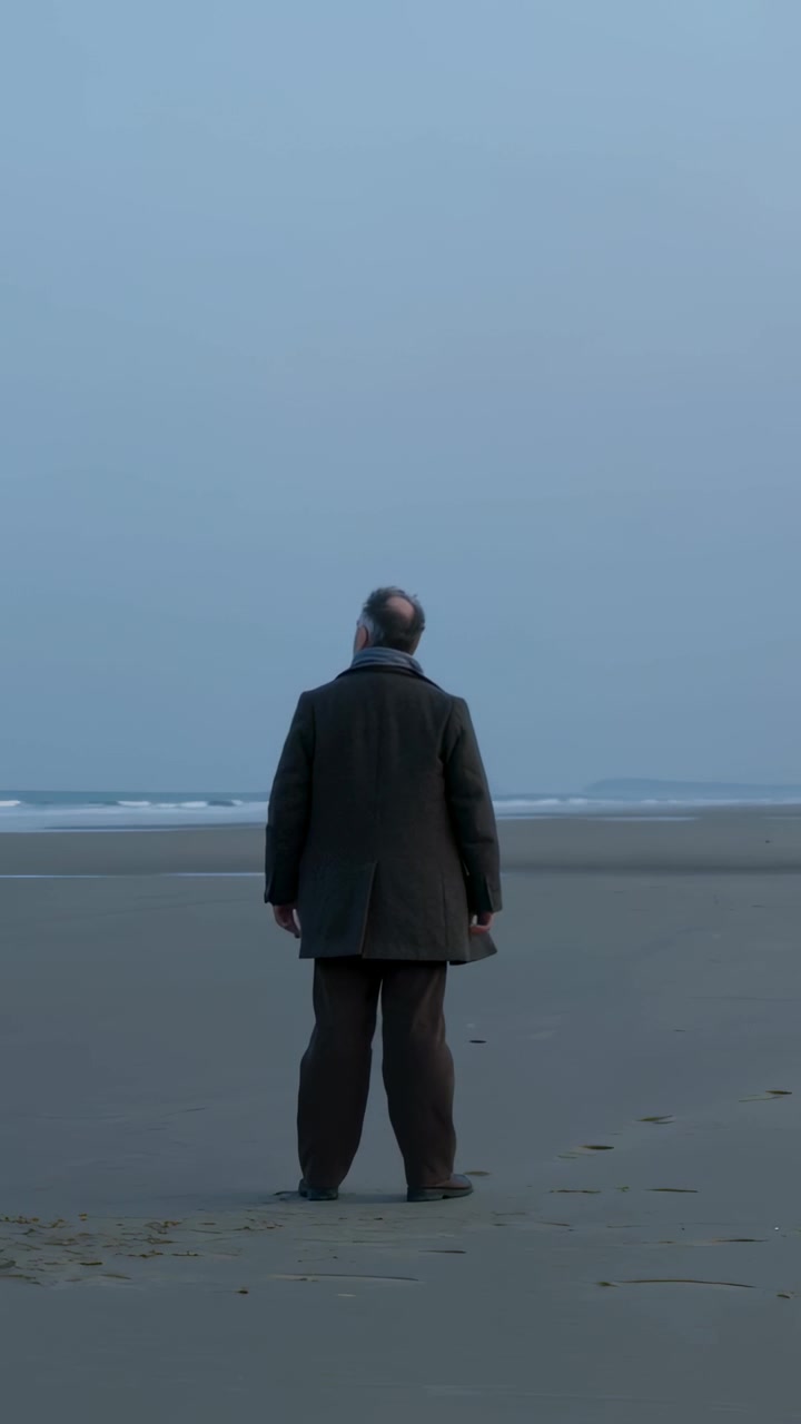 Vertical video: Walking to shore, senior man wearing coat and scarf, stopping and watching horizon