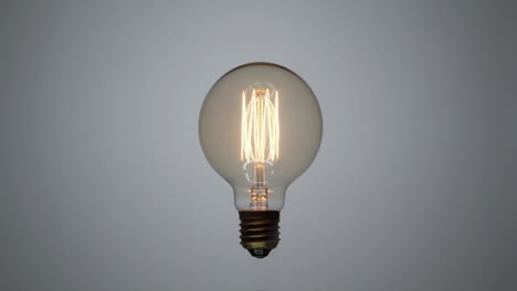 tungsten light bulb flickering over white background.