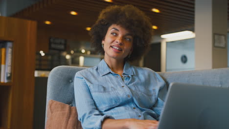 Young-Businesswoman-In-Modern-Open-Plan-Office-Working-On-Laptop-In-Casual-Seating-Area