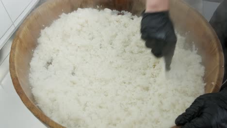 cook stirs hot rice in a wooden bowl