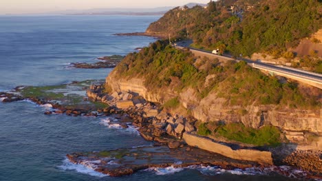 sunset view at the sea cliff bridge along pacific ocean in new south wales, australia - aerila drone shot
