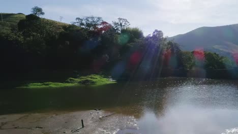 aerial moving show over lake with sunlights revealing vast atlantic forest valley