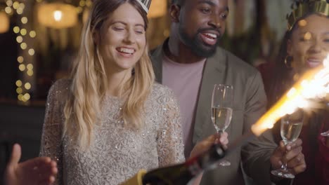 plano medio de amigos celebrando la víspera de año nuevo con champán y bengalas