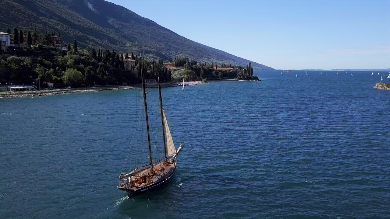 화창한 날 배경에 해안선이 있는 라고 디 가르다(lago di garda)에 있는 유서 깊은 범선의 공중 촬영