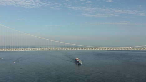 cargo container ship sailing towards large suspension bridge at akashi kaikyo