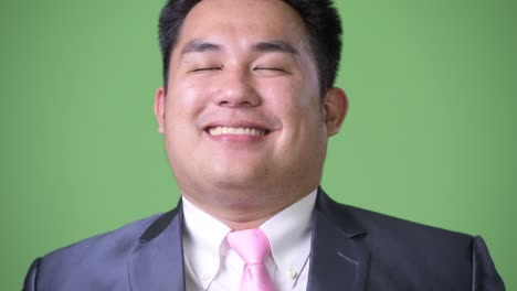 초록색 배경에 젊은 잘생긴 과체중 아시아 사업가