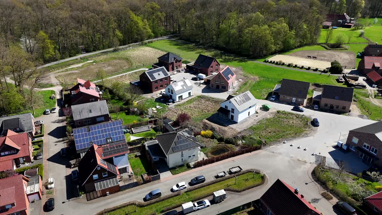 Construction site with new Building Single family houses with solar panels on roof. Sunny day with forest trees in spring season. Aerial approaching shot.