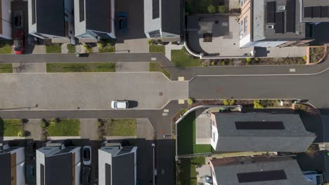 aerial sweep over semi-detached solar-roof homes with minimalist landscaping and tidy paved street illustrating eco-conscious modern family housing