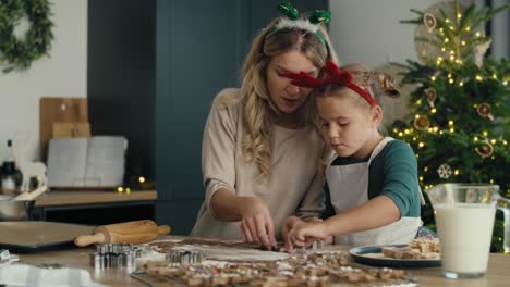mujer caucásica con su hija haciendo galletas en navidad en la cocina.
