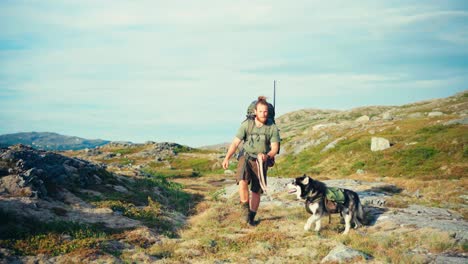 backpacker with alaskan malamute dog walking on a sunny day