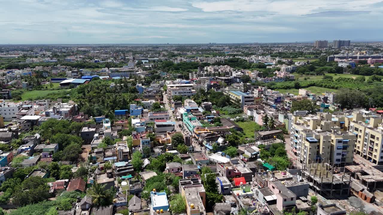 Life in the metro: a moving drone shot above a vibrant, dense neighborhood with a mix of old and new architecture. The cityscape extends toward a distant industrial area