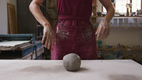 mid section of female potter wiping her hands on apron at pottery studio