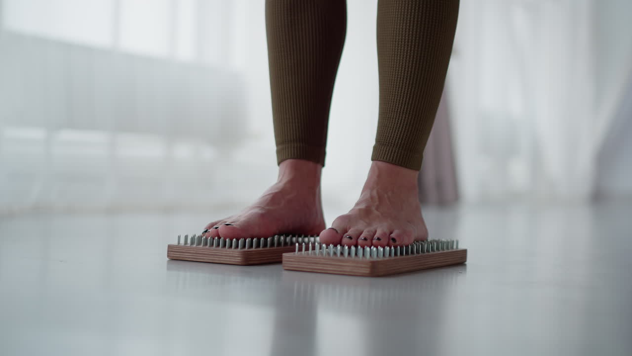 Leg view trainer standing on two different nail mat in bright studio focusing on grounding balance wellness energy under soft ambient light showing strength and discipline