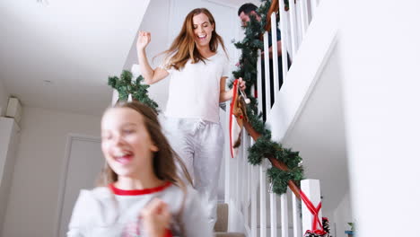familia emocionada con pijama corriendo por las escaleras sosteniendo medias en la mañana de navidad