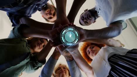 animation of clock over work colleagues stacking hands in background