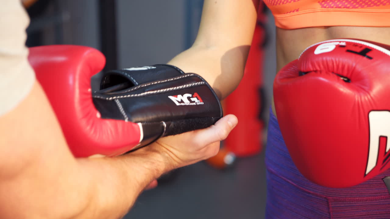 VINNITSA, UKRAINE - December 2017: Young male coach helps to put on boxing gloves to the sportswoman. Healthy lifestyle.