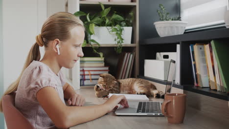 the child is working on a laptop at home, next to it is a cup of tea. distance learning concept