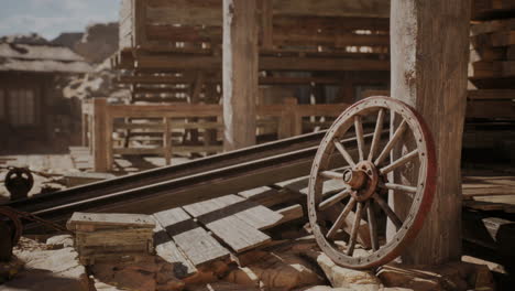 old wooden wagon wheel resting on the ground in a rustic storage area