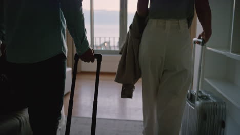 happy travel couple arriving in hotel room on honey moon vacation looking out window view enjoying romantic holiday together