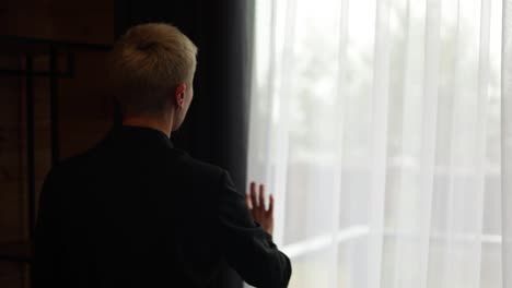 woman looking out the window with a drink